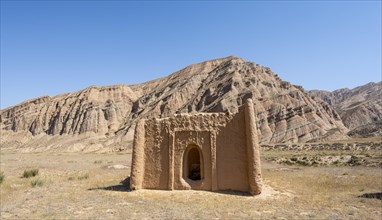 Clay mausoleum, tombstones, old Kyrgyz cemetery, between dry eroded landscape, Naryn region,