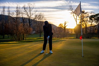 Female Golfer Concentration on the Putting Green on Golf Course in Sunset in Switzerland