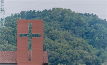 Large Christian cross attached to roof of house in countryside