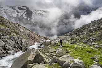 Mountaineer at a mountain stream, Furtschaglbach, cloudy mountains in the background,