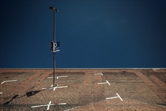Street lamp and car park sign against a clear blue sky on a brick wall, Cologne Deutz, North