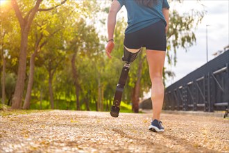 Close-up rear view of a disabled man with prosthetic leg running outdoors