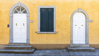 White arched front doors in pastel-coloured house wall, Sant'ilario in Campo, Elba, Tuscan