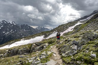 Mountaineer on hiking trail with snow, Berliner Hoehenweg, mountain landscape with rocky peaks,