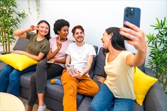 Multi-ethnic friends having fun taking a selfie sitting together in a couch at home