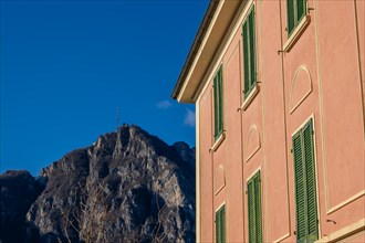 Old Building with Window Against Blue Clear Sky and Mountain Peak San Salvatore in Campione