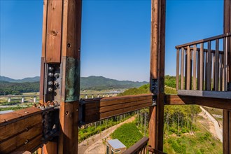 Wooden beams of tower on mountain top at public park with view of landscape and structures below in