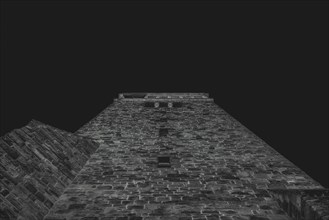 View from below of an old tower in black and white at night, creates a mystical atmosphere,