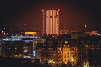Illuminated skyscraper dominates the cityscape at night under an orange-red sky, Sparkasse Tower,