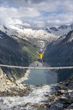 Mountaineer jumping on a suspension bridge over a mountain stream Alelebach, picturesque mountain