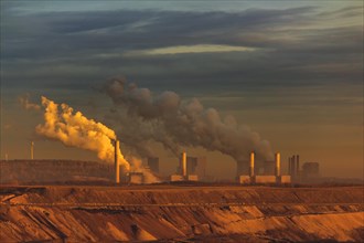 Chimneys emitting smoke in a twilight industrial landscape, open-cast lignite mine, North