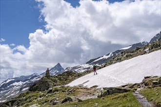 Mountaineer on a rocky hiking trail in a snowfield, Berliner Hoehenweg, mountain landscape with