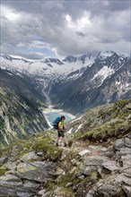 Mountaineer on hiking trail, view of Schlegeisspeicher, glaciated rocky mountain peaks Hoher