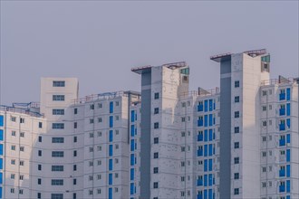 New highrise apartments with unfinished white concrete exterior walls and blue coverings on widow