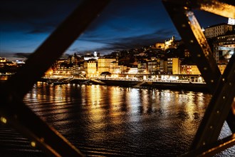 Night view of riverside in Porto with famous iron bridge in the front, Portugal, Europe