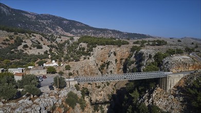 Metal bridge over a gorge with parked cars and mountain backdrop, Aradena Gorge, Aradena, Sfakia,