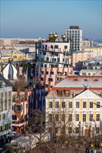 Hundertwasser House Green citadel with golden spheres stands out between buildings, Magdeburg,