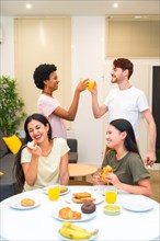 Vertical photo of a group of multi-ethnic friends enjoying and celebrating while eating breakfast