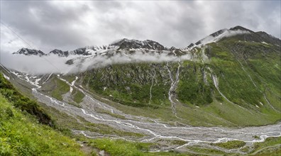 Cloudy valley of Schlegeisgrund with mountain stream, glaciated mountain peaks Hoher Weiszint and