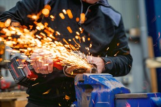 Sparks flying while a worker man working with electric grinder tool on steel structure in factory
