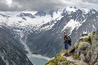 Mountaineer on hiking trail, view of Schlegeisspeicher, glaciated rocky mountain peaks Hoher