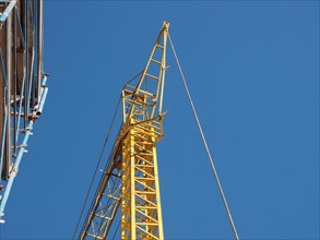 Yellow tower crane and scaffolding over blue sky