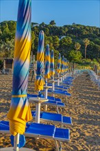 Sun loungers and parasols on Straccolignino beach at sunrise, near Capoliveri, Elba, Tuscan