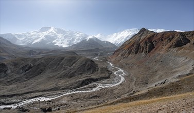 Valley with river Achik Tash, behind glaciated and snow-covered mountain peak Pik Lenin and Pik of