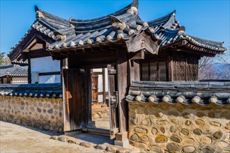 Traditional gate with ceramic tile roof set in mud stone wall at display of Korean architecture in
