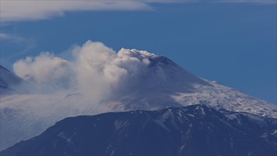 Mount Etna. Smoke rises from a snow-covered volcano under a clear blue sky, Etna, Taormina, Eastern