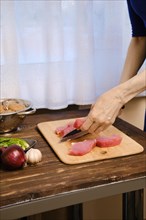 Hands of unrecognizable woman cutting pork fillet for stew