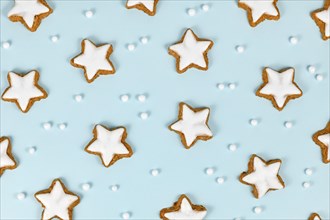 Top view of German star shaped glazed cinnamon Christmas cookies called 'Zimtsterne' on light blue