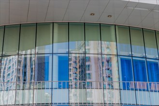 Low angle view of brick and glass office building with reflections of surrounding buildings in