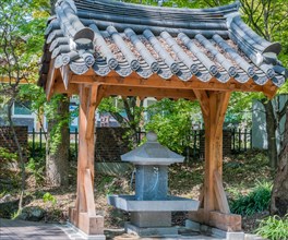 Concrete water fountain under gate like structure with ceramic tile roof in public park