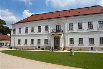 Baroque castle with white facade and red roof, path leading to a central door, Esterhazy Castle,