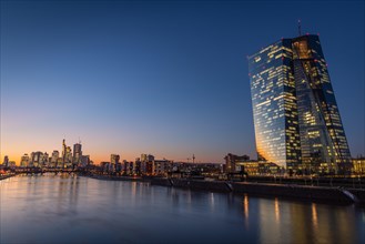The lights of the European Central Bank (ECB) and the Frankfurt banking skyline glow in the