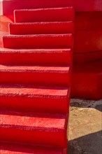Extreme closeup red concrete stair at base of lighthouse on sunny day