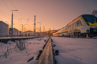 Train on snow-covered tracks at sunset with focus on foreground, Pforzheim, Germany, Europe