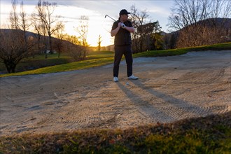 Male Golfer Concentration in the Sand Trap on Golf Course in Sunset in Switzerland