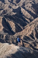 Hiker walking along a canyon, eroded hilly landscape, Badlands, Valley of the Forgotten Rivers,