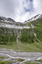 Mountain streams flow over steep mountain slopes into the Schlegeisgrund valley, cloudy rocky
