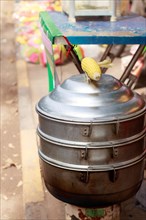 Vertical view of a metal steamer for cooking whole corn cob at the sidewalk, a popular khmer