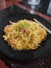 Close up to a plate of pancit bihon or Filipino stir-fried rice noodles, authentic local