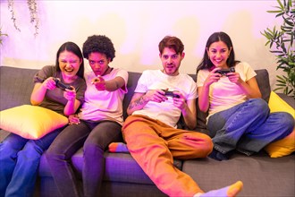 Frontal view of a happy and competitive multi-ethnic friends playing console at home