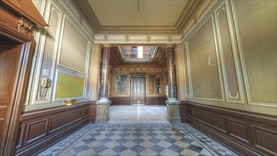 A hallway in a historic building with chequered floor tiles and pillar panelling, Villa Woodstock,