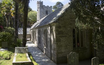 Historic gravestones and church amidst sub-tropical plants, St Just in Roseland, Cornwall, England,