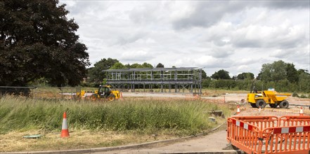 Steel frame of new building at construction site with machinery, Melton, Suffolk, England, UK