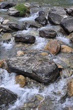 Boulders in fast flowing mountain stream, Pyrenees, France, Europe