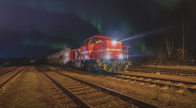 Red locomotive at night with northern lights in the background on an industrial track, Ruhr area,