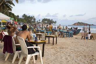 People sitting at tables of beach bar, Mirissa, Sri Lanka, Asia